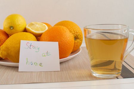 A cup of tea with lemon on a background of oranges. Set of vitamins becouse of corona virus. Stay at...