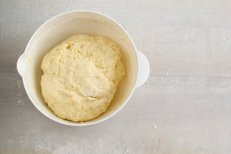 Raw dough in a white plastic plate on the table. Preparation for cooking. Top view