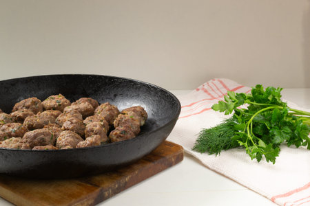 Homemade fried meatballs with herbs in a pan on a white background. Swedish traditional cuisine.