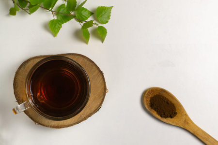 Tea in a glass cup and chaga powder in a wooden spoon .Top view. Copy space.の写真素材