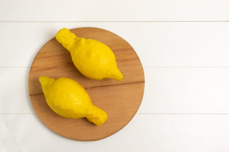 Ugly lemons on a wooden cutting board on a white background. Top view. Horizontal orientation. The...
