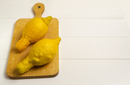 Ugly deformed lemons on a wooden cutting board on a white background. Close-up. Horizontal...