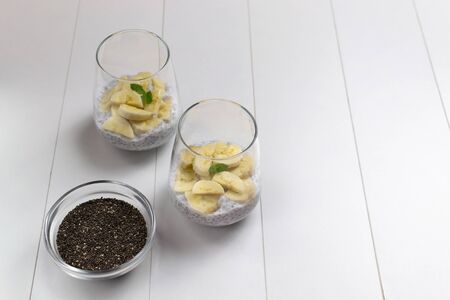 Chia pudding with mint leaves in glass cups with grains in a bowl on a white background. Copy space. A healthy breakfast consists of yogurt and grains, mint can be added for flavor. Horizontal orientation. Selective focusの写真素材