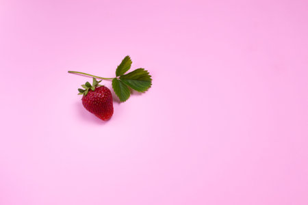 Juicy strawberries and a green leaf on a colored background. The concept of minimalism. Top view. Copy space. Horizontal orientation.の写真素材