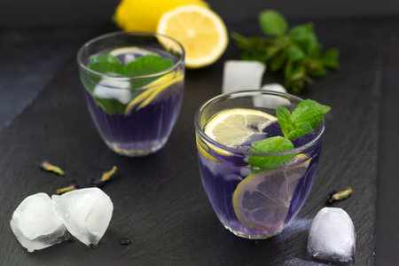 Anchan refreshing blue Thai tea in glass glasses with ice and lemon on a black background.の写真素材