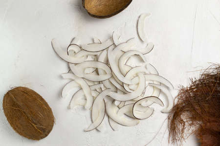 Natural homemade coconut chips on a white background. Dried snacks in the home kitchen. Top view. Horizontal orientation. Selective focus.の写真素材