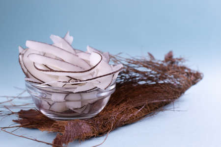 Natural homemade chips in a glass bowl on a dried palm leaf on a blue background. Snacks prepared in the home kitchen. Copy space. Selective focus.の写真素材