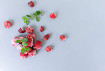 Frozen strawberries with sprigs of lemon balm on a gray background. Top view. Copy space.の写真素材