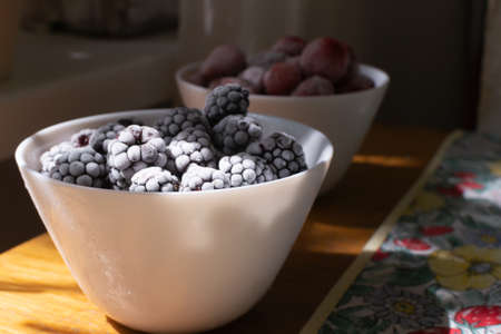 Frozen berries in white bowls on a wooden table. Selective focus. Horizontal orientation.の写真素材