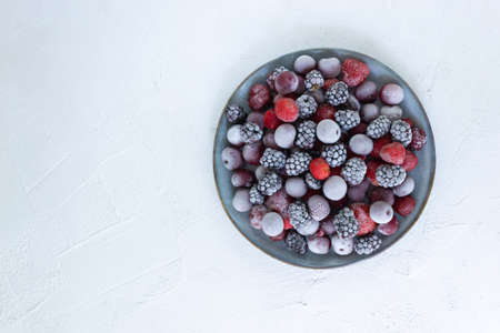 Frozen berries in a gray plate on a white background. Harvesting berries for winter. Copy space. Top view.の写真素材