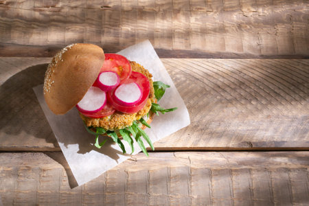 Vegetarian burger with chickpea cutlet and vegetables on a blue background. Vegan food concept. Copy...