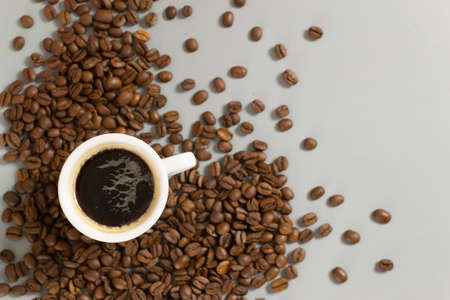 White cup with espresso among coffee beans on a gray background. Close-up. Selective focus. Copy space. Top view.の写真素材