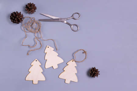 Wooden Christmas tree toys with a cord and scissors on a gray background. Natural Christmas decor concept. Copy space. Top view.の写真素材