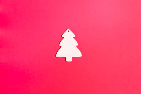 Wooden Christmas tree toy on a red background. Natural Christmas decor concept. Copy space. Top view. Horizontal orientation. Minimalism.の写真素材