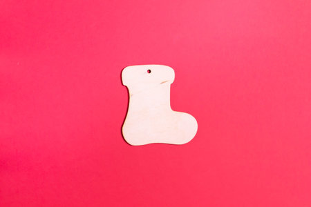 Christmas tree decoration wooden boot on a red background. Natural Christmas decor concept. Copy...