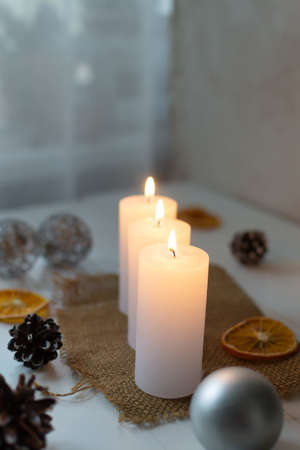 Three burning candles on the background of Christmas decor. Christmas card.の写真素材