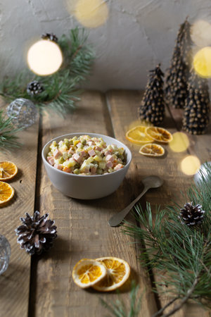 Festive Olivier salad russian in a bowl with a spoon on a wooden background. Traditional Russian cuisine. Top view. Copy space. Rustic style.の写真素材