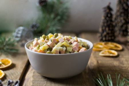 Traditional Olivier salad russian in a bowl on a wooden background. Festive Russian cuisine. Copy space. Rustic style. Horizontal orientation.の写真素材