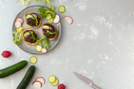 Chia seed snack on baguette slices with vegetables on a gray plate on a gray background. Top view. Copy space. Horizontal orientation.の写真素材
