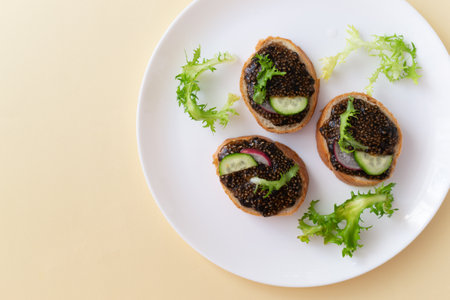 Chia seed sandwiches on pieces of baguette with cucumber, radish and herbs on a white plate on a yellow background. Healthy food concept. Copy space. Top view. Horizontal orientation.の写真素材