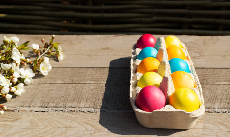 Easter colorful eggs with a branch of a blossoming apple tree on a wooden background. Christian...
