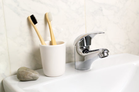 Two bamboo toothbrushes stand in a glass in the bathroom. Eco friendly stuff concept. Horizontal orientation.の写真素材
