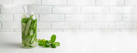 Water is poured into the jug. Fresh water infused with cucumbers and mint sprigs, detox drink. Health care, fitness, healthy food concept. Banner.の写真素材