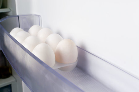 White chicken eggs lie in a mold on the refrigerator door. Healthy nutrition concept. Copy space....