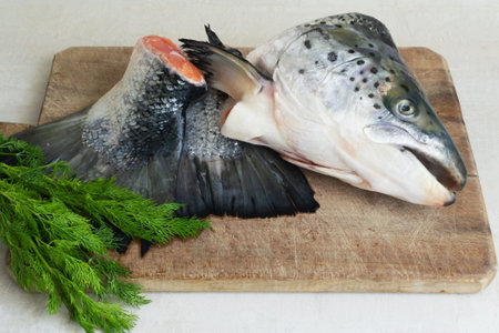 Salmon head and tail with a bunch of dill on a wooden cutting board. Cooking fish soup. Lohikeitto...
