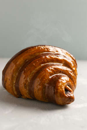 Freshly backed french croissant with chocolate filling lies on the table. Delicious French pastries. Copy space. Close-up. Selective focus. Vertical orientation.の写真素材