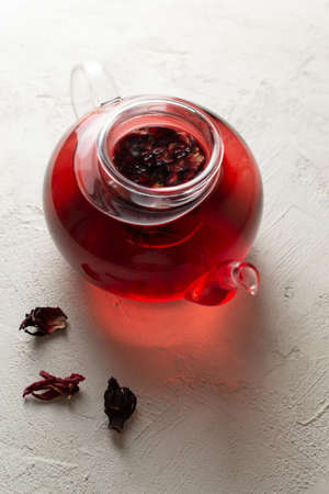 Glass teapot with brewed hibiscus leaves on a white background. Red tea. Alternative medicine concept. Rosella or Sudanese rose flowers are a very popular drink in Arab countries.の写真素材