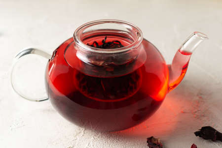 Glass teapot with brewed hibiscus leaves on a white background. Red tea. Traditional drinks concept. Rosella or Sudanese rose flowers are a very popular drink in Arab countries.の写真素材