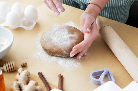A woman prepares honey - cinnamon cookies. The finished dough is sprinkled with flour for further...