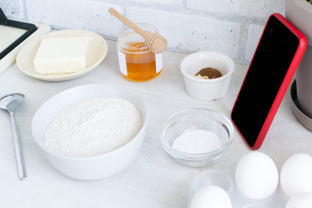 The concept of online lessons in the preparation of cookies. A smartphone in a red case and...