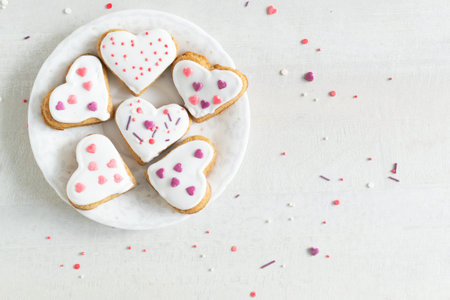 Gingerbread covered with white icing and sprinkling on a light saucer on a light background. The...