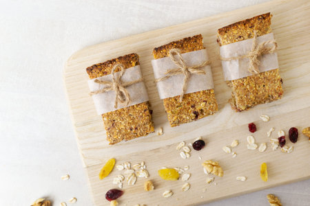 Several pieces of energy bars lie on a wooden board with ingredients. Healthy food concept....