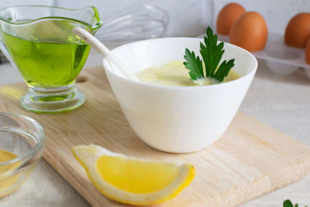 Homemade mayonnaise in a white bowl with parsley leaf and olive oil. The concept homemade food. horizontal orientation.の写真素材