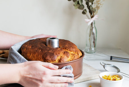 A woman puts a raisin pie in an aluminum mold on a wooden cutting board in the kitchen. A sweet,...