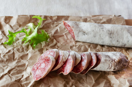 Traditional Catalan thin sausage - fuet. Pieces Pork sausage with mold on craft paper. horizontal...
