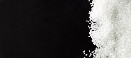 Banner. Black background, sprinkled with white sea salt. Rough texture. Salt is suitable for cooking...