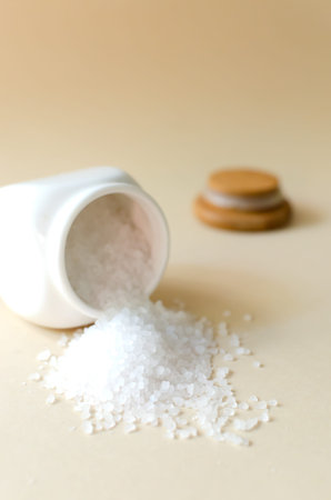 White sea salt is pouring out of the white hodgepodge. Rough texture. Salt is suitable for cooking...
