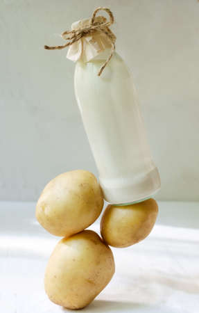 Glass bottle with potato milk on the table. A new trend in eating healthy. Food levitation concept. Vegetable Milk for Vegans. vertical orientation.の写真素材