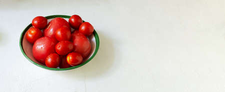 Red ripe tomatoes of different sizes in a ceramic deep bowl on a white background. farming concept. Banner. horizontal orientation. selective focus. copyspace.の写真素材