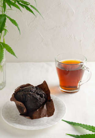 Marijuana cupcake muffins with cannabis leaves and a cup of herbal tea. gluten-free. Alternative sweet concept. vertical orientation. selective focus.の写真素材