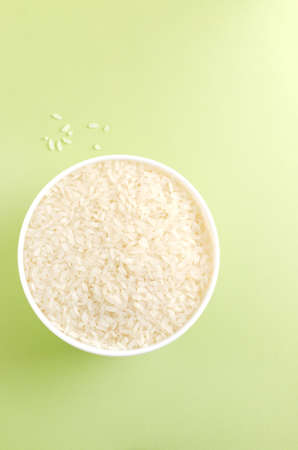 Dry camollino rice in a white ceramic bowl on a green background. The concept of vegan food. Healthy eating. copyspace. selective focus. vertical orientation.の写真素材