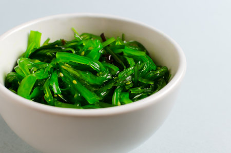 Hiyashi Wakame Chuka or seaweed salad in a white bowl on a gray background. The concept of traditional oriental food. Vegetarian food. horizontal orientation.の写真素材