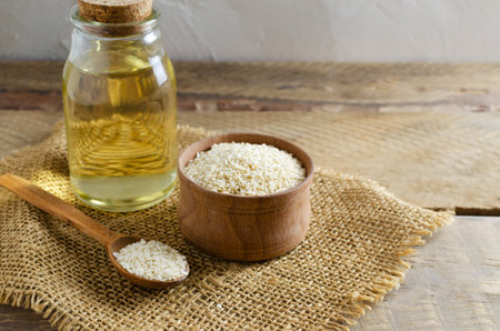 Sesame oil in glass jar with seeds in wooden bowl and spoon on wooden table. concept of healthy eating. horizontal orientation. copyspace.の写真素材