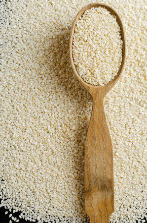 Wooden spoon with sesame seeds. Concept of healthy food. vertical orientation