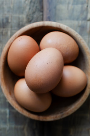 Many chicken eggs in a wooden bowl on burlap on a wooden background. rustic style. The concept of organic food. vertical orientation. top view.の写真素材
