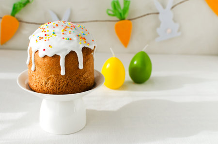 Traditional Ukrainian cake on a stand with candles in the shape of eggs on a white tablecloth. The...